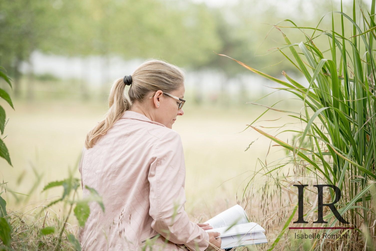 Isabelle mit Buch sitzend auf der Wiese